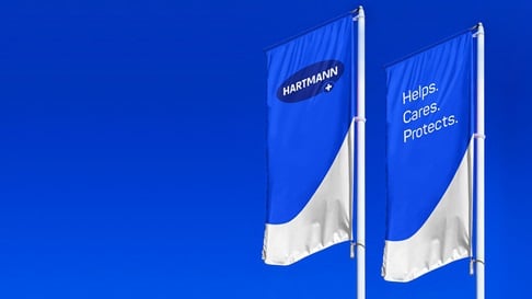 Two blue flags with HARTMANN lettering and the HARTMANN slogan "Helps. Cares. Protects."