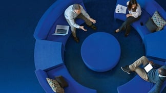 Three team members sit in a circle and discuss.